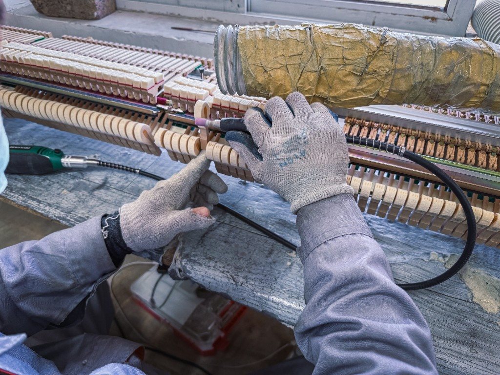 Technician refurbishing piano action components in the workshop
